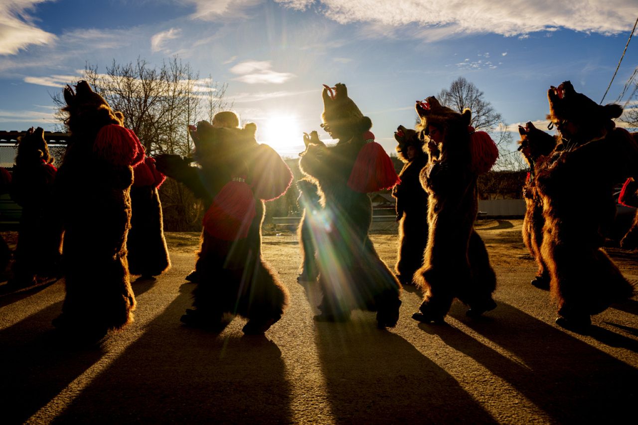 Members of the Sipoteni bear pack walk in Vasieni, northern Romania, Tuesday, Dec. 26, 2023, while touring village homes to perform the ritual bear dance.