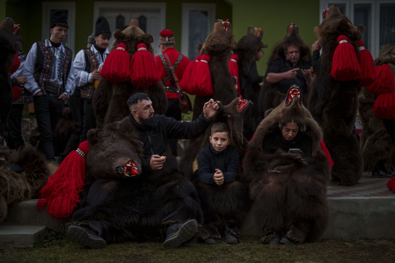 Members of the Sipoteni bear pack relax after their performance in Preluci, northern Romania, Tuesday, Dec. 26, 2023.