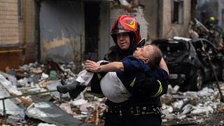 A firefighter carries a man from a damaged residential building after a Russian missile strike, in Kyiv, Ukraine, Tuesday, Jan. 2, 2024.
