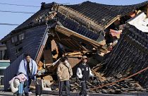 Un uomo porta le sue cose davanti a una casa crollata in seguito a un terremoto a Wajima, nella prefettura di Ishikawa, in Giappone, martedì 2 gennaio 2024\. 