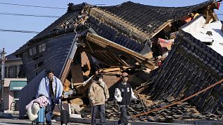A man carries his belongings past a collapsed house following an earthquake in Wajima, Ishikawa prefecture, Japan, Tuesday, 2 January 2024. 
