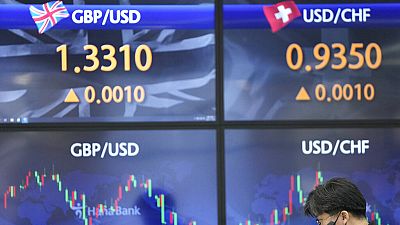A currency trader talks near the screens showing the foreign exchange rates at a foreign exchange dealing room in Seoul, South Korea, Friday, Nov. 26, 2021. Asian stock market