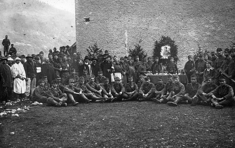 Katonák egy csoportja fotózkodott 1917 karácsonyán az olaszországi, Fastro-ban I. Károly osztrák császár, IV. Károly magyar király képével