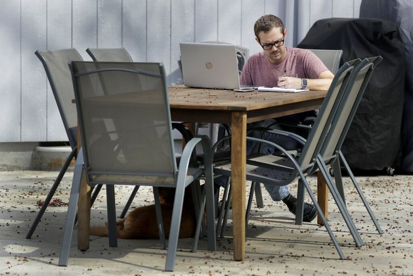 Un homme travaille sur son ordinateur dans le jardin de sa maison à Overland Park, KS, mars 2020