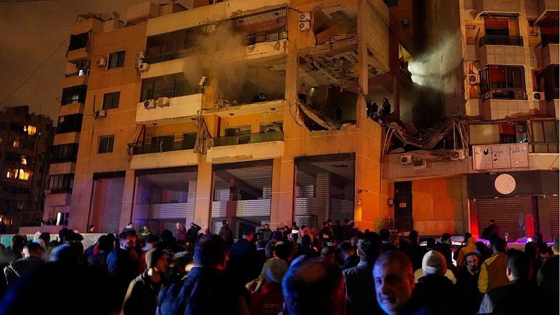 People gather outside a damaged building following a massive explosion in the southern Beirut suburb of Dahiyeh, Lebanon, Tuesday, Jan. 2, 2024.
