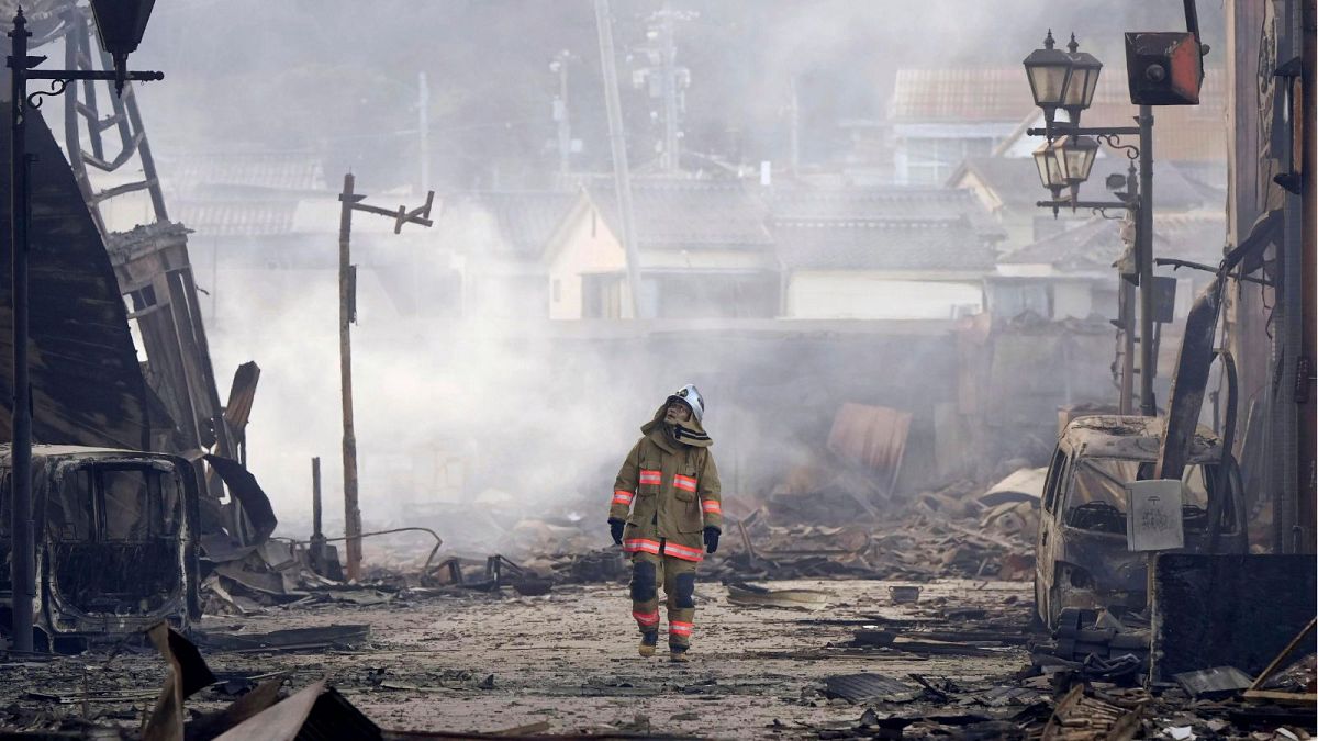 A firefighter walks through the rubble and wreckage of a burnt-out marketplace following earthquake in Wajima, Ishikawa prefecture, Japan Tuesday, Jan. 2, 2024.