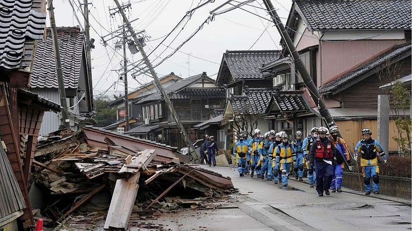 Police walk past collapsed houses hit by earthquakes in Suzu, Ishikawa prefecture, Japan Wednesday, Jan. 3, 2024.