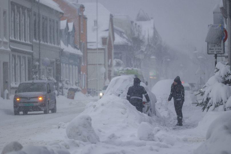 Ανθρωποι προσπαθούν να καθαρίσουν το χιόνι από ένα όχημα, στο Kristiansand, Νορβηγία, Τρίτη, 2 Ιανουαρίου 2024. F
