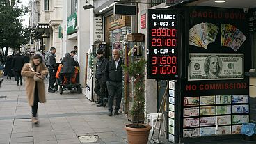 Peple walk next to an exchange currency shop in Istanbul, Turkey, Thursday, Dec. 21, 2023. Turkey's central bank hiked its key interest rate by 2.5 percentage points on Thursd
