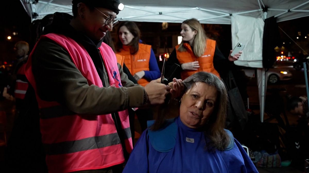 Un coiffeur en train de couper les cheveux d'une femme dans un salon de coiffure
