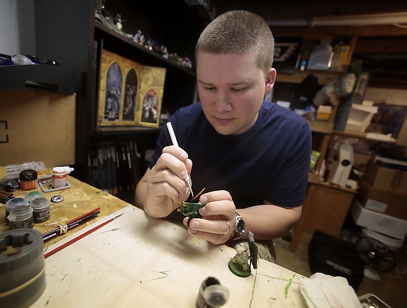 Thomas Severson hand paints one of his thousands of Warhammer 40,000 miniatures in Dubuque, Iowa.