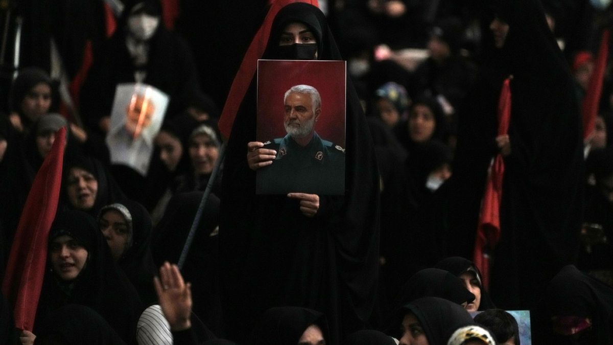 A woman holds up a poster of the late Revolutionary Guard Gen. Qassem Soleimani at the Imam Khomeini grand mosque in Tehran, Iran, Wednesday, Jan. 3, 2024.