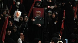 A woman holds up a poster of the late Revolutionary Guard Gen. Qassem Soleimani at the Imam Khomeini grand mosque in Tehran, Iran, Wednesday, Jan. 3, 2024.