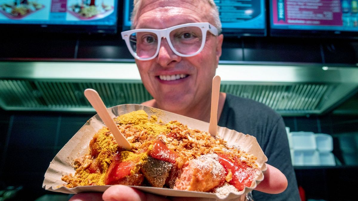 Ο Lars Obendorfer, ιδιοκτήτης του λουκάνικου "Best Worscht in Town", κρατάει λουκάνικα με κάρυ vegan.