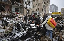 Volunteers and residents clear the debris of an apartment building destroyed by a Russian attack in Kyiv.