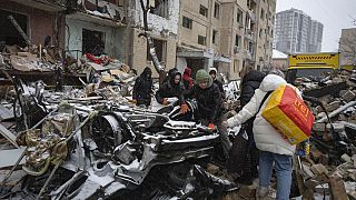 Volunteers and residents clear the debris of an apartment building destroyed by a Russian attack in Kyiv.