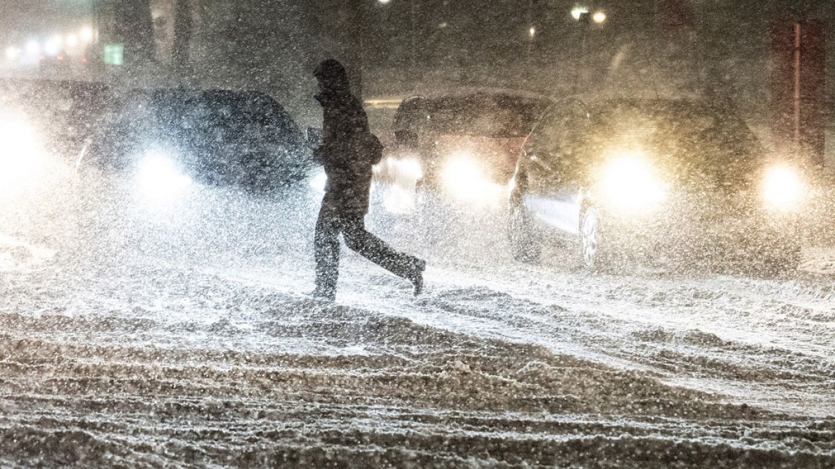 A person crosse a street during heavy snowfall in Aalborg, northern Jutland, Denmark, Wednesday, Jan. 3, 2024.