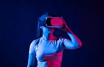 Young woman wearing a virtual reality headset goggles and playing a game in metaverse.