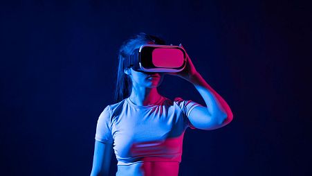 Mujer joven con gafas de realidad virtual y jugando un juego en metaverso.