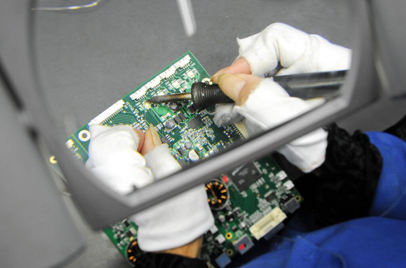 A person does detail work of soldering on a circuit board in Hillsboro, OR, September 2010