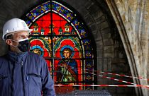 French President Emmanuel Macron stands by a stained glass at the reconstruction site of the Notre-Dame de Paris cathedral on April 15, 2021.