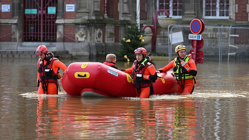 Rescue workers evacuate a person as the Aa river floods Arques, northern France, 4 January 2024.