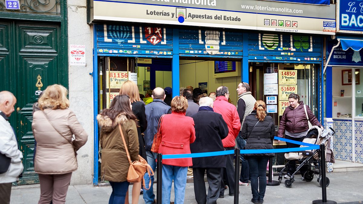 Un grupo de gente hace cola para comprar en Doña Manolita, la administración de lotería más famosa de España.