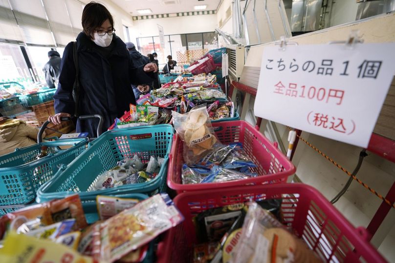 100 yen karşılığında bazı yiyecek ve diğer ürünleri sunan bir süpermarketten alışveriş yapan bir kişi