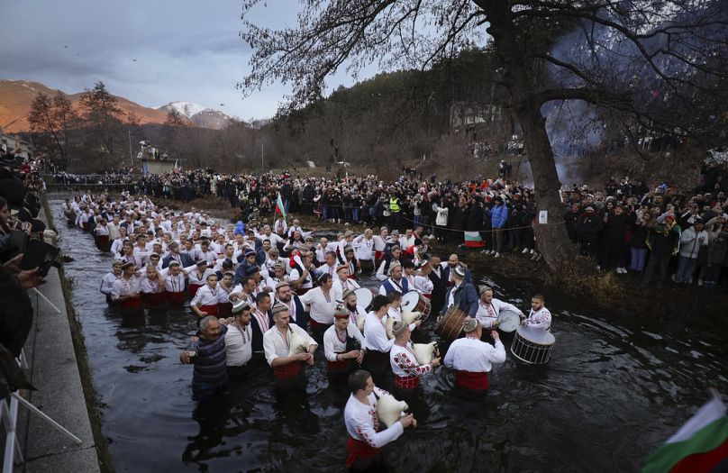 Men play bagpipes and drums as they wade into the cold Tundzha River to celebrate Epiphany, in the town of Kalofer, Bulgaria, Saturday, Jan. 6, 2024.