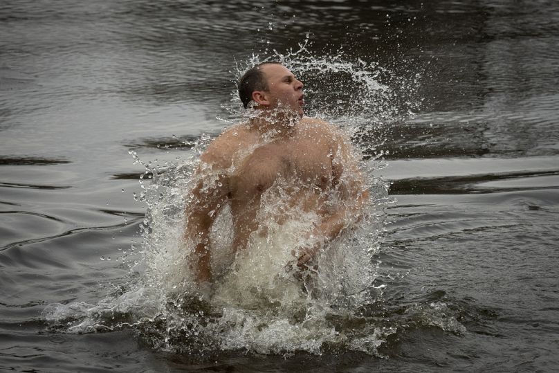 A man gestures in icy water of the Dnipro, during a traditional Epiphany celebration in Kyiv, Ukraine, Saturday, Jan. 6, 2024.