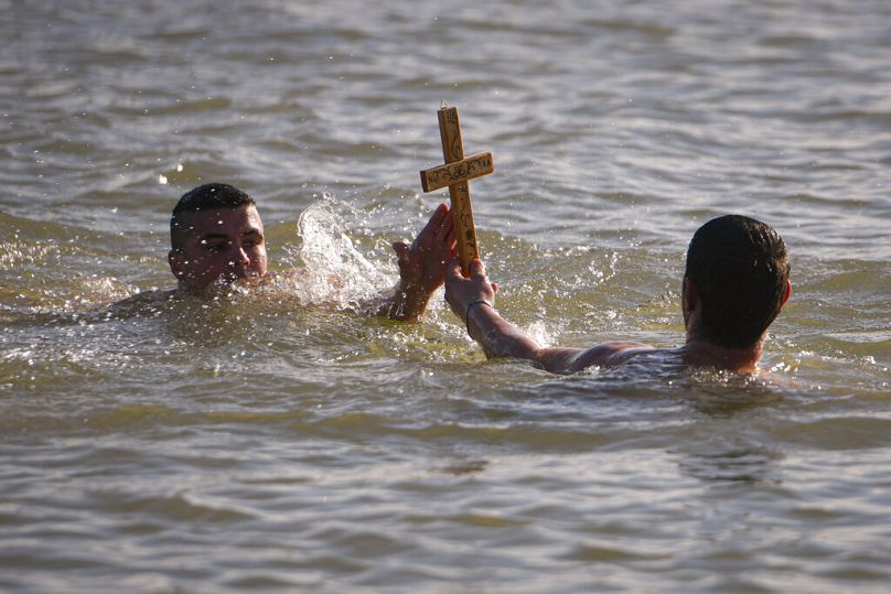 Swimmers hold a wooden cross they retrieved from the Danube river during Epiphany celebrations in Facaieni, eastern Romania, Jan 6 2024.