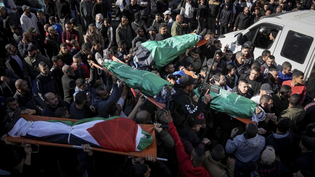 Mourners carry the bodies of six Palestinians, some are draped in the Hamas flags during their funeral in the West Bank city of Jenin on Sunday, Jan. 7, 2024.