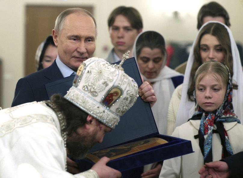 Russian Orthodox Archbishop of Odintsovo and Krasnogorsk Foma (Nikolay Mosolov), foreground, kisses an icon as Russian President Vladimir Putin, left, stands nearby.