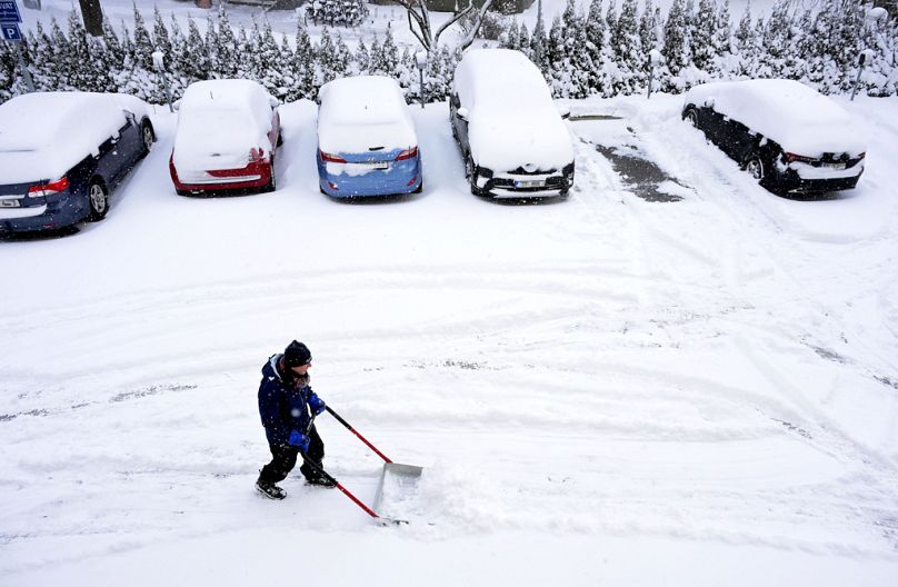 Μετά την έντονη χιονόπτωση της νύχτας, ένας άνδρας εργάζεται με ένα φτυάρι για να απομακρύνει το χιόνι από τις θέσεις στάθμευσης σε ένα κτίριο κατοικιών στη Στοκχόλμη, Πέμπτη,
