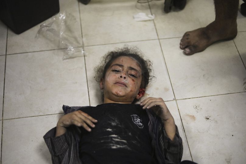 İsrail saldırısında yaralandıktan sonra Gazze'deki Nasır Hastanesi'ne getirilen ancak yer olmadığı için zeminde yatırılan bir Gazzeli çocuk tedavi için beklerken