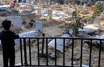  A Palestinian child looks at the graves of people killed in the Israeli bombardment of the Gaza Strip and buried inside the Shifa Hospital grounds in Gaza City on 31 Dec. 