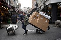 Two men pull trollies with goods in a street market in a commercial district in Istanbul, Turkey, Thursday, Dec. 21, 2023. Turkey's central bank hiked its key interest rate by