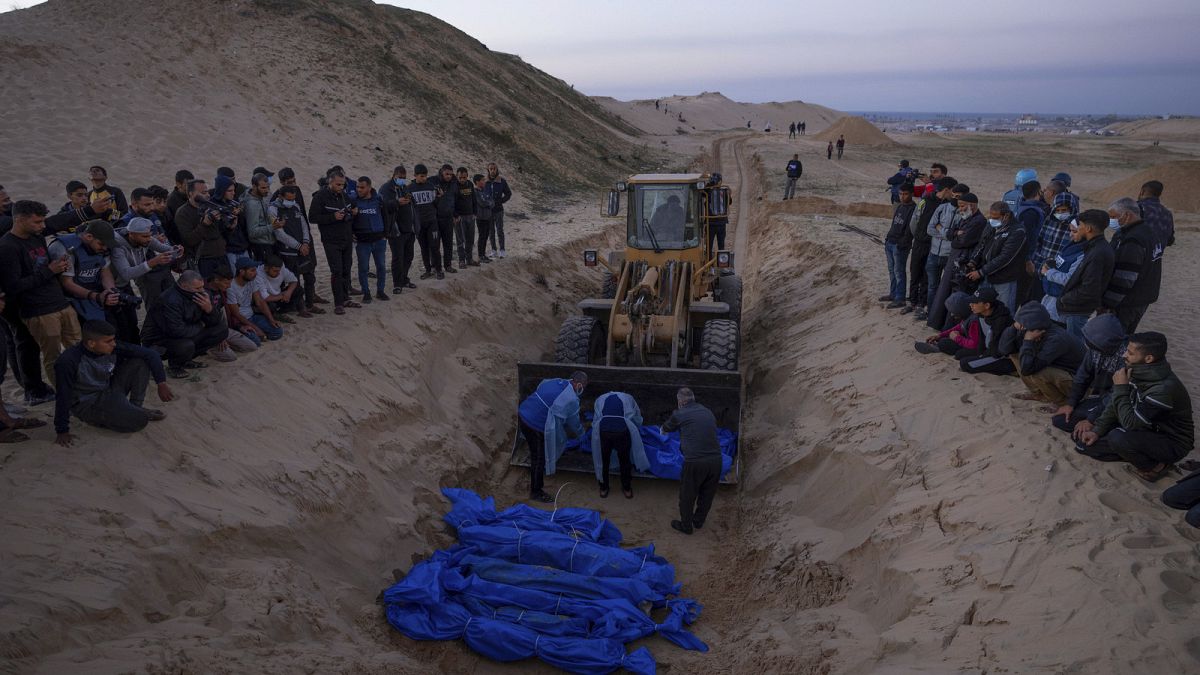 A bulldozer unloads the bodies of Palestinians killed in fighting with Israel and turned over by the Israeli military during a mass funeral in Rafah, Gaza Strip