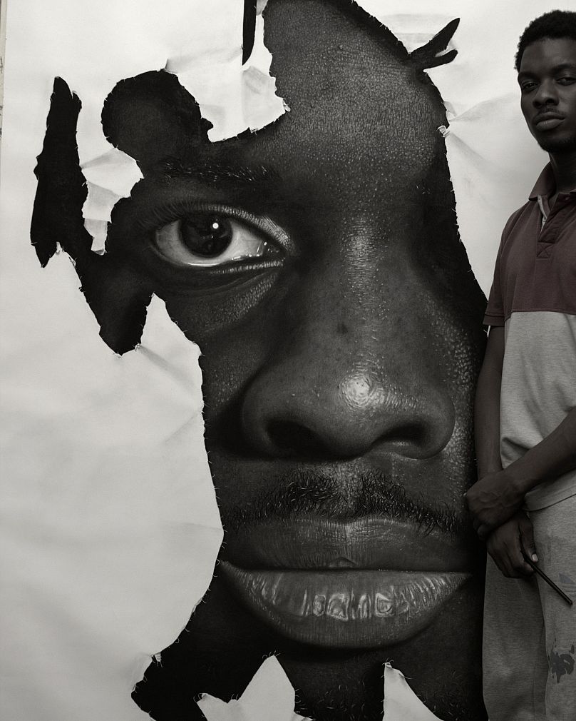 Ken Nwadiogbu poses next to one of his hyperrealistic artworks