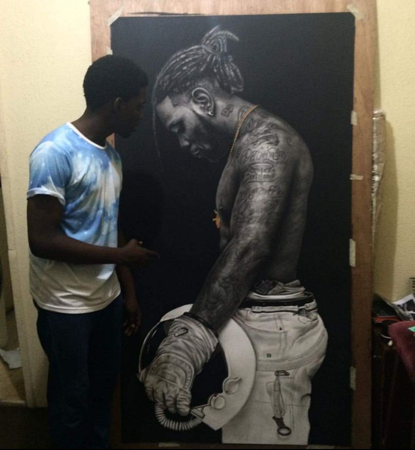 Ken Nwadiogbu photographed in front of his cover artwork for Burna Boy's 'On a Spaceship'