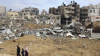 عائلة فلسطينية تسير أمام المباني المدمرة في قطاع غزة.