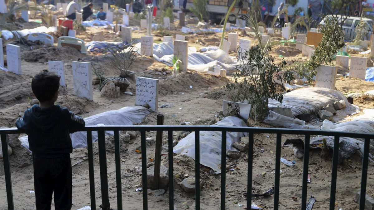 Ένα παλαιστινιακό παιδί κοιτάζει τους τάφους των ανθρώπων που σκοτώθηκαν κατά τους ισραηλινούς βομβαρδισμούς της Λωρίδας της Γάζας και θάφτηκαν μέσα στον χώρο του νοσοκομείου Σίφα στην πόλη της Γάζας τον Δεκέμβριο
