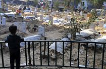 A Palestinian child looks at the graves of people killed in the Israeli bombardment of the Gaza Strip and buried inside the Shifa Hospital grounds in Gaza City in December