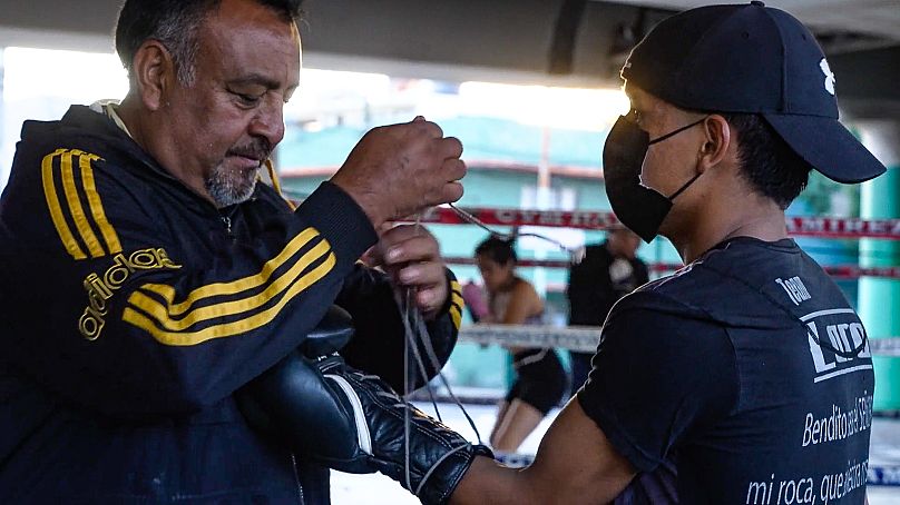 Miguel Ramirez tightens the glove of his grandson Josafat Hernández Cervantes