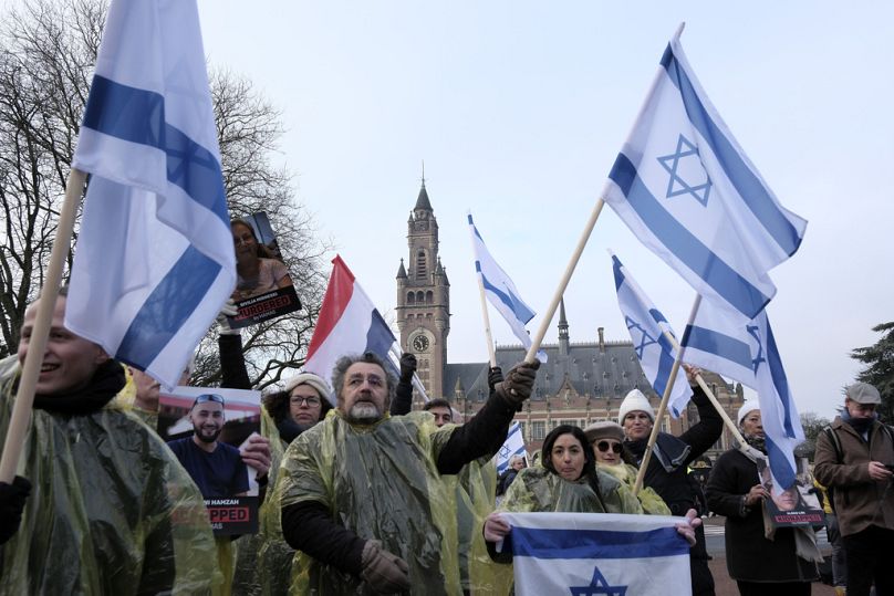 Protestors wave Israeli flags, and hold photos of the hostages kidnapped by Hamas, during a demonstration outside the International Court of Justice in The Hague on Thursday