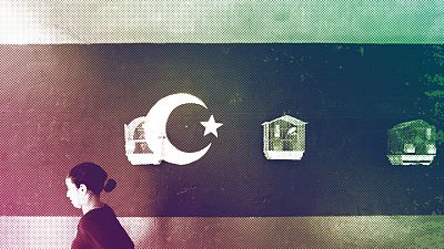 A young Libyan girls walks by pet birds in cages hanging from a wall painted with the rebel flag in the rebel-held Benghazi, July 2011