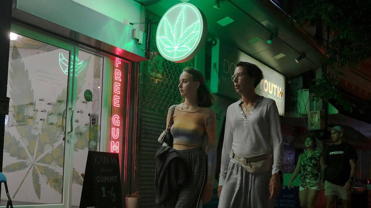 Touristen gehen am 10. August 2022 in Bangkok, Thailand, an einem neu zugelassenen Cannabisladen vorbei. 