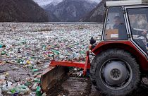 A worker uses a tractor to push the waste back in the Drina river near Visegrad, Bosnia, 10 January 2024.