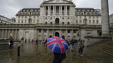 A woman with an umbrella stands in front of the Bank of England, at the financial district in London, Thursday, Nov. 3, 2022. 