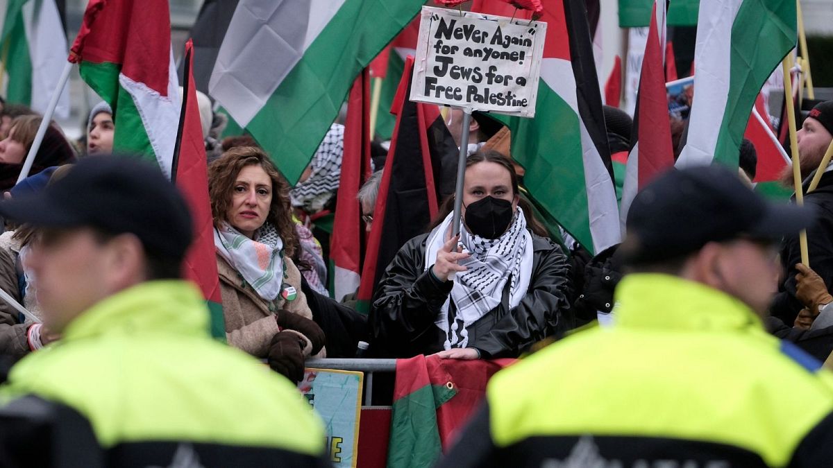 معترضان به همراه پرچم‌ها و بنرهایی در خارج از دیوان بین‌المللی دادگستری در لاهه هلند، جمعه، ۱۲ژانویه ۲۰۲۴ 